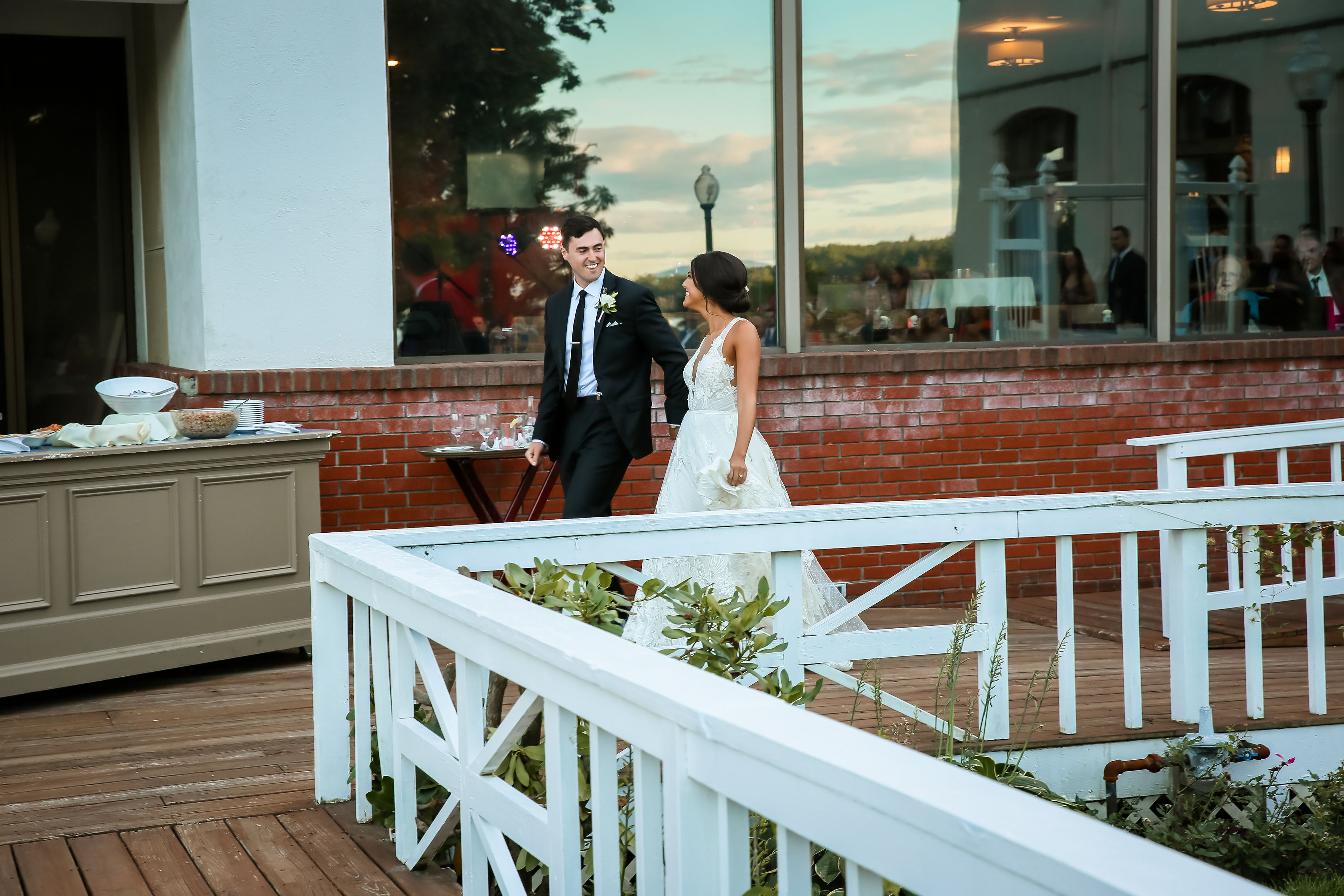 wedding couple walks across outdoor deck