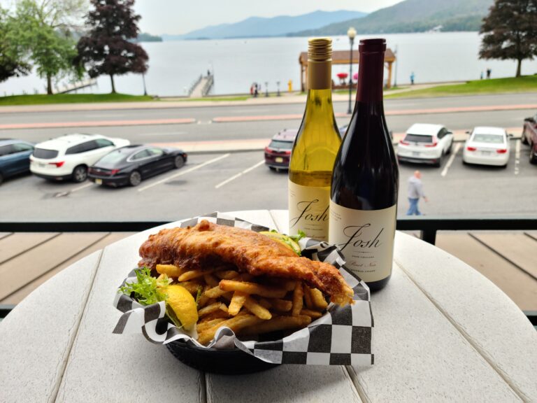 Chicken and fries and wine glass on table overlooking lake george