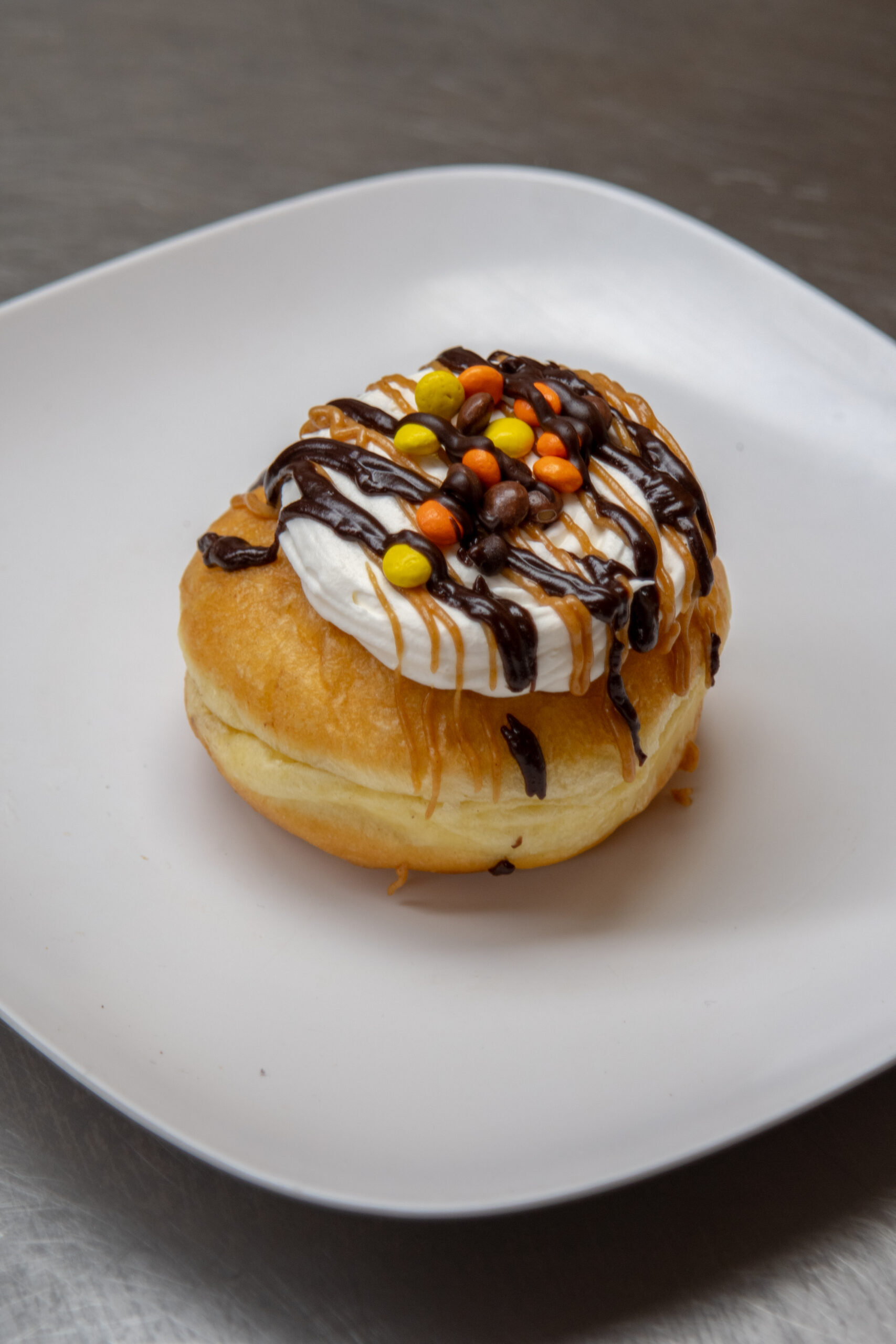 Bombolini donut with reeses pieces drizzled with chocolate and peanut butter
