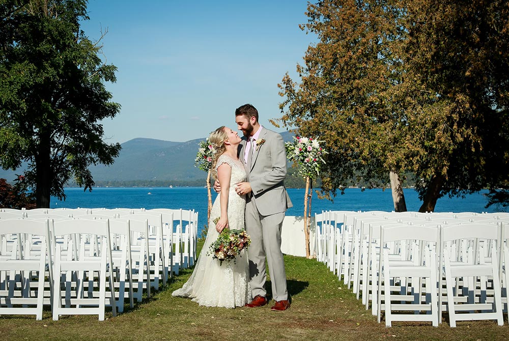 Bride and groom pose for photo among empty chairs