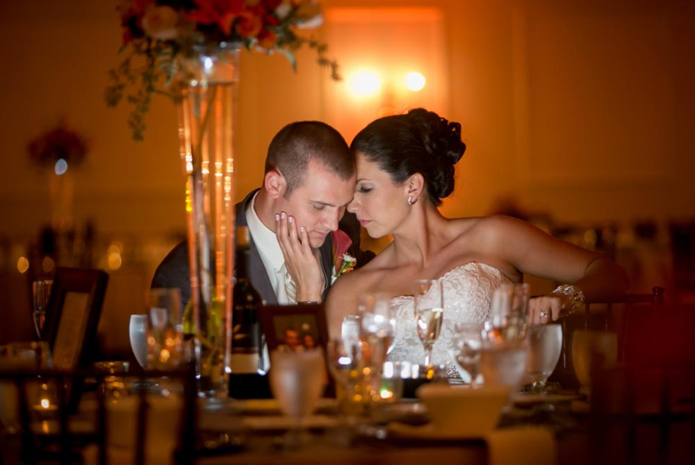 Bride and Groom embrace sitting at table